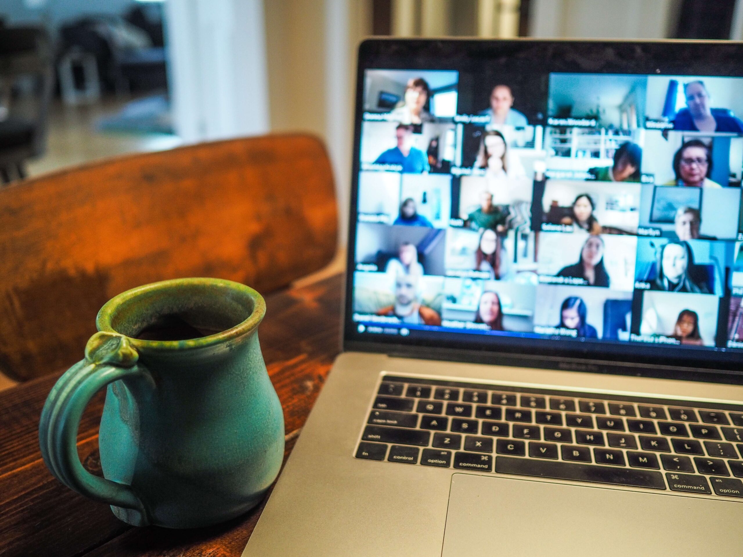 PCに映るオンライン会議参加者の顔と机に置かれたコーヒーの画像
