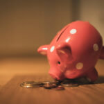 豚の貯金箱が小銭を見つめている画像