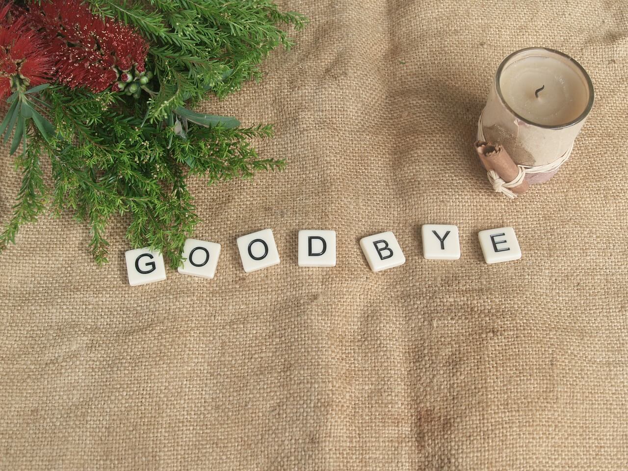 布の上にキャンドルと花と「GOODBYE」と書かれたブロックがおかれている画像