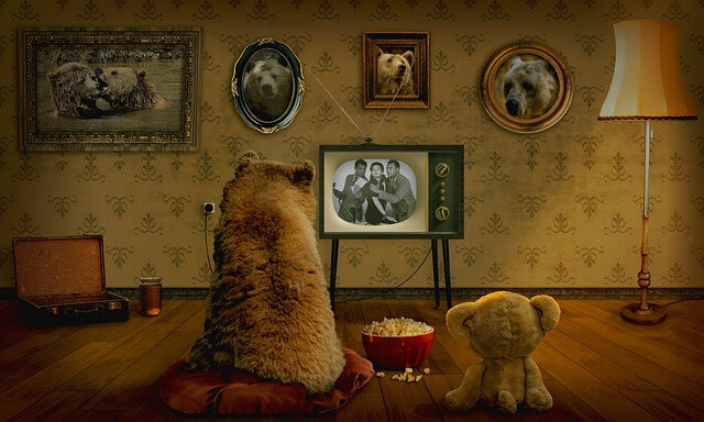 クマと熊のぬいぐるみがよりそってテレビを見ている画像